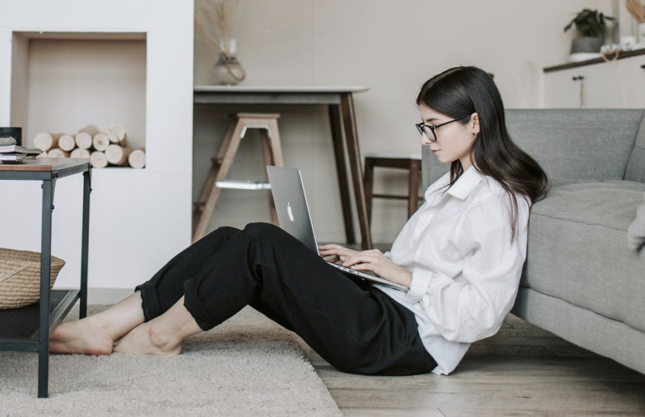 Femme travaillant à distance dans son salon avec un ordinateur portable, illustration du télétravail et de la flexibilité professionnelle