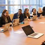 Collègues autour d'une table de réunion avec des ordinateurs portables lors d'une discussion en équipe